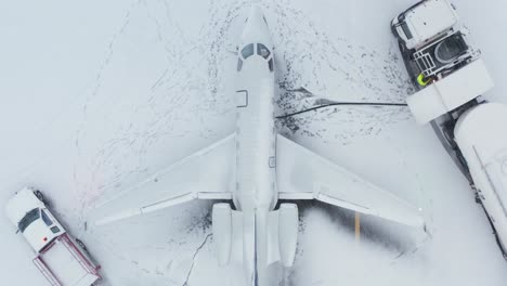 Top-down-view-business-jet-being-refueled-by-fuel-truck,-winter-season