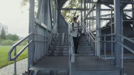 man walking with bicycle up metal stairs