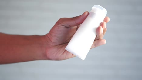 hand holding a white plastic bottle