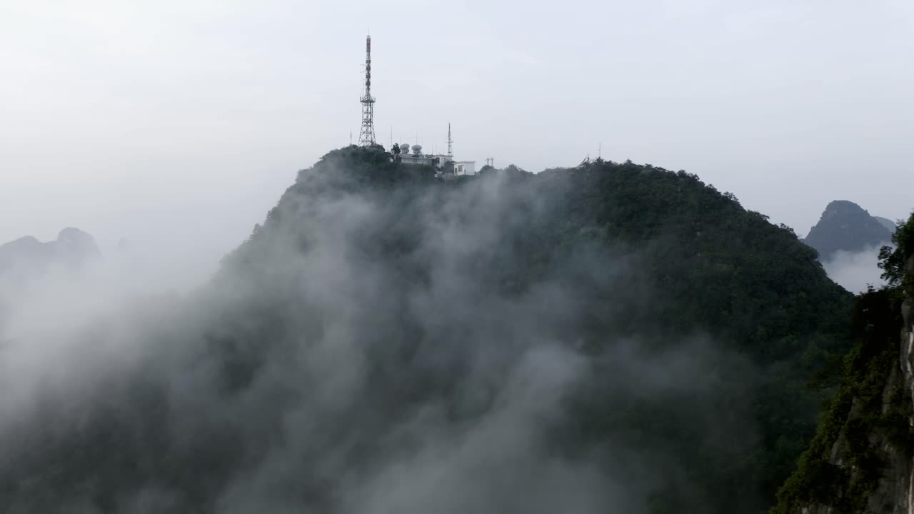 yangshuo 산 4k 드론은 안개 낀 구름 위의 tv 타워에서 뒤로 물러납니다.