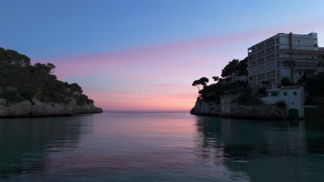 Aguas-Tranquilas-De-La-Bahía-Con-Nubes-Rosadas-Al-Atardecer-En-El-Horizonte-En-Palma-De-Mallorca