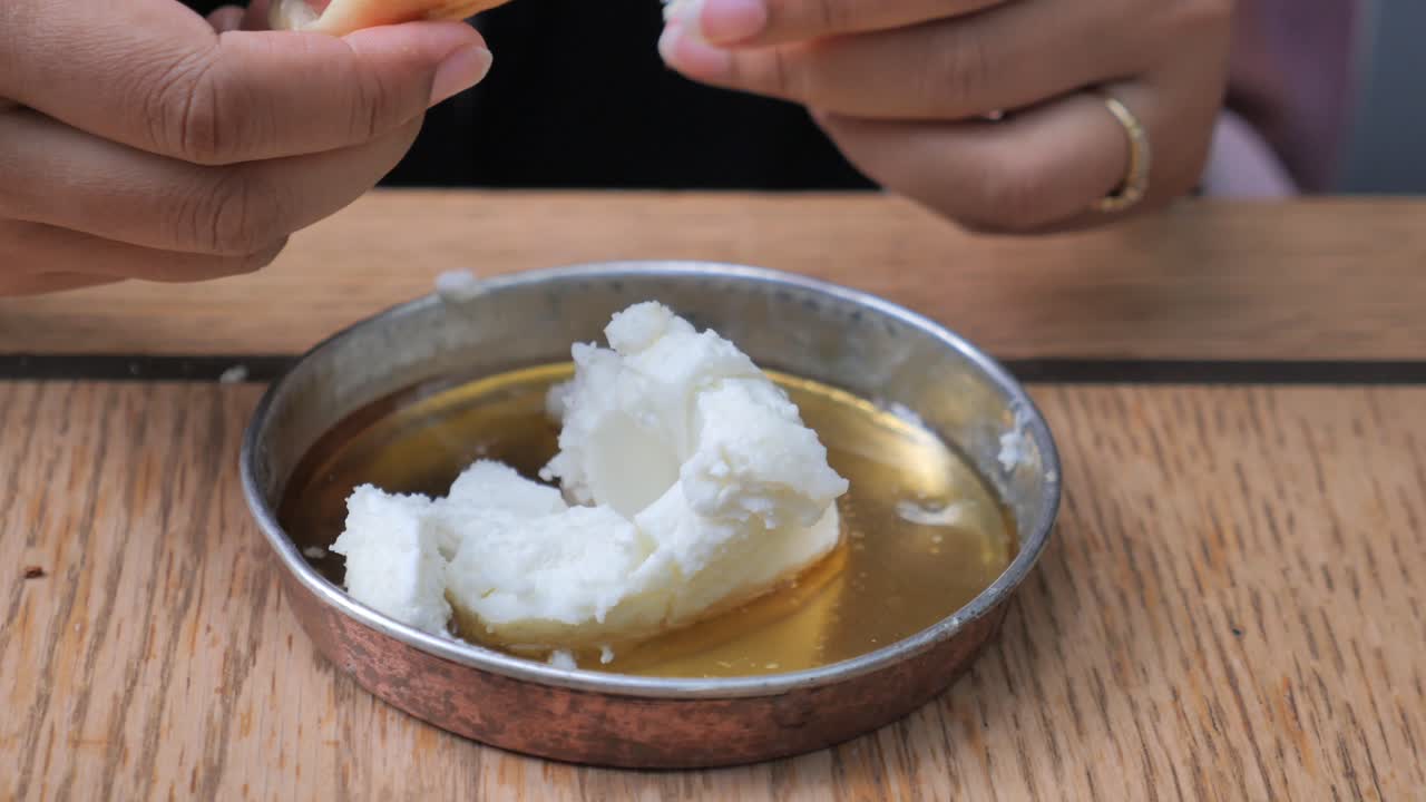 Woman eating Turkish breakfast with bread, butter and honey