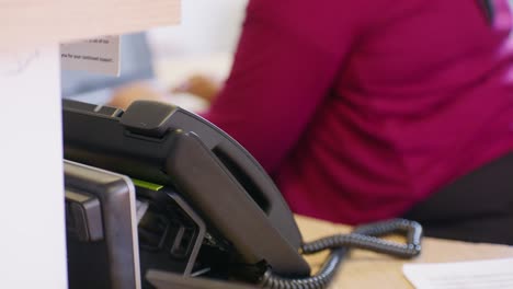 receptionist answering a phone in a uk gp practice