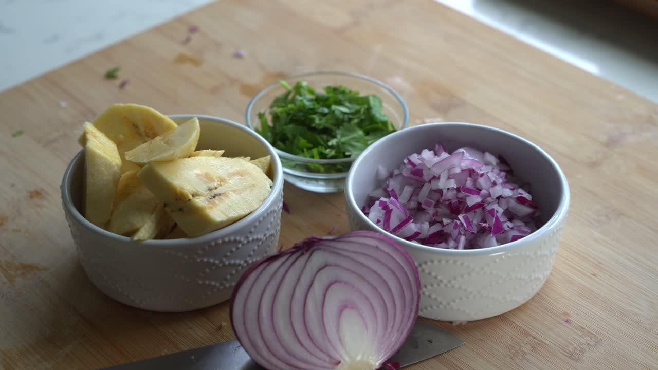Panning shot of red onions and special ingredients to cook a meal two cans of beans rice plantain avocado red onion and cilantro