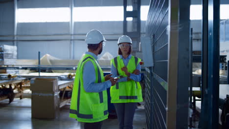 Two-uniformed-manufacture-workers-checking-production-process-inspecting