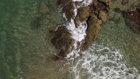 tropical-waves-break-slowly-over-craggy-rocks