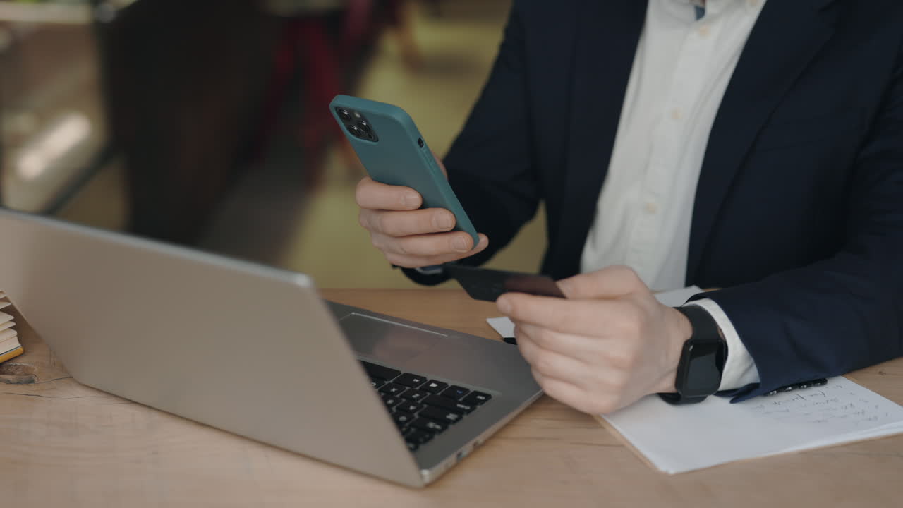 Person using laptop and smartphone with a credit card