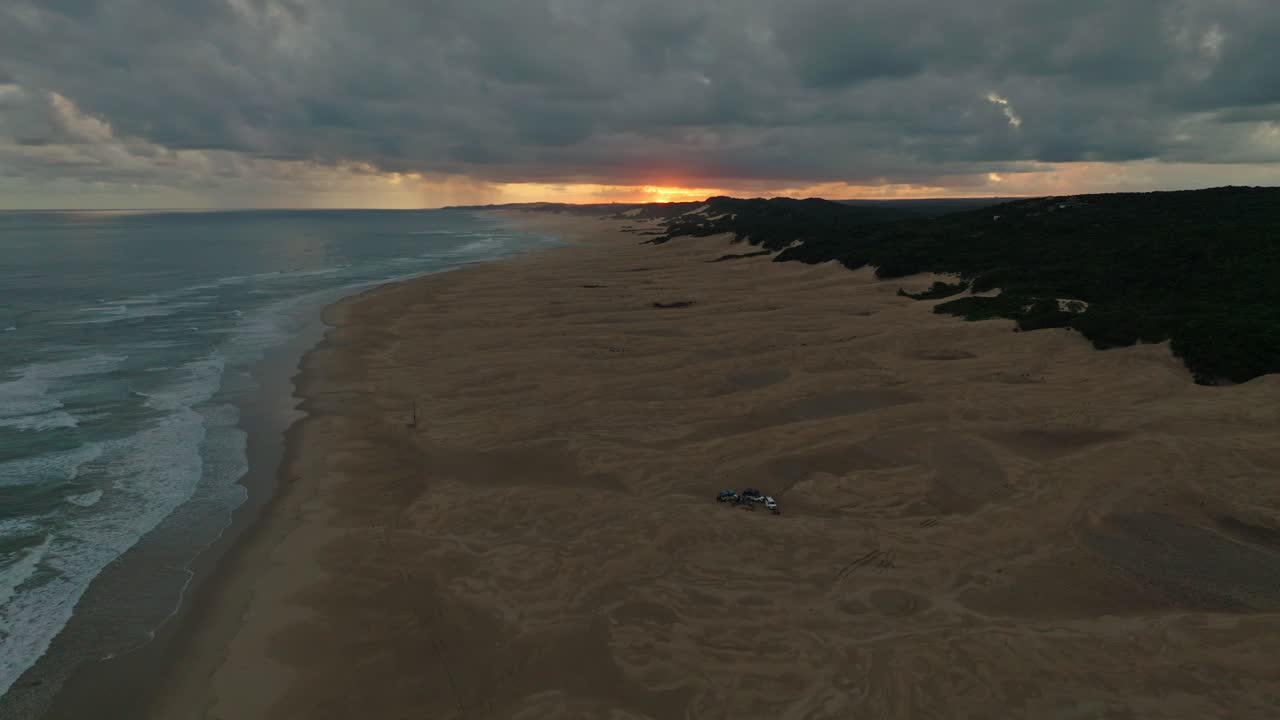 3 coches fuera de carretera acampando en la playa durante el atardecer