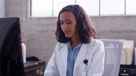 young female doctor using computer at office desk, close up