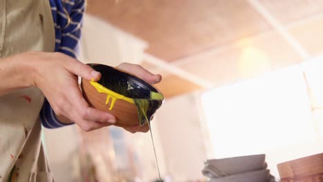 Female-potter-pouring-paint-into-bowl