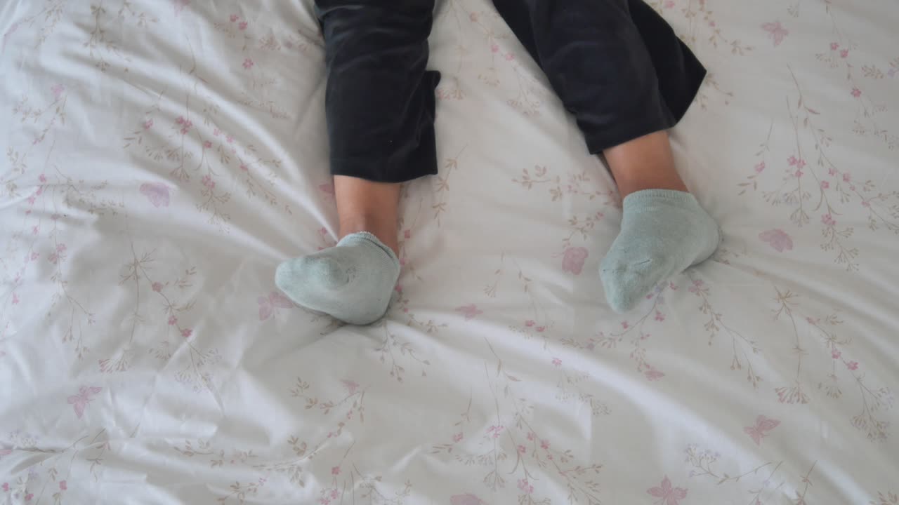 Legs and Feet Wearing Socks on a Floral Bedsheet