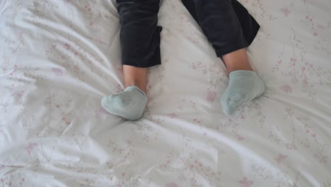 legs and feet wearing socks on a floral bedsheet