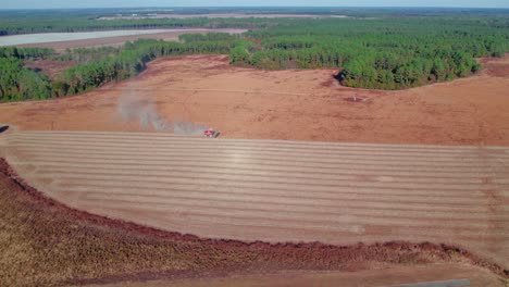 Harvesting-non-gmo-soybeans-Georgia-USA-red-green-tractor-vehicle-releasing-clouds-of-smoke-behind-moving-forward-slowly-in-line-collecting-product-plant-placed-close-to-road-cars-driving-by-nature