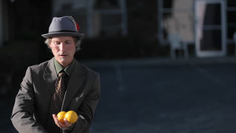 un uomo fa un atto di giocoleria usando tre palline arancioni