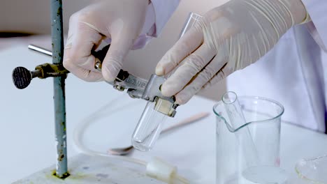 hands manipulating test tube clamp in laboratory setting