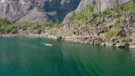 turistas de drones aéreos en el bosque montañoso de skardu pakistán tomando un paseo en bote a motor en hermosas aguas azules en el lago kachura superior en un día soleado de verano