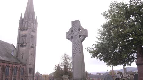 stone cross grave in graveyard in front of old european church in inverness, scotland in the highlands