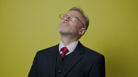 portrait of a senior businessman. grey-haired mature man with glasses in elegant costume on yellow studio background.