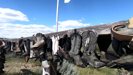 Botas-De-Vaquero-Colgando-De-Un-Poste-De-Madera-En-El-Campo-En-Un-Día-Soleado