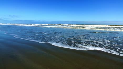 Reflexiones-Del-Cielo-Azul-En-Una-Playa-De-La-Costa-Oeste-De-Nueva-Zelanda