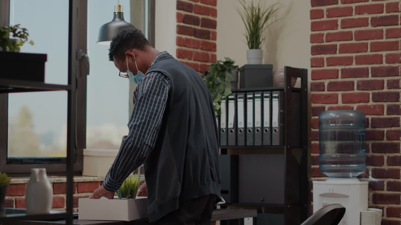 Frustrated person with face mask packing up office things