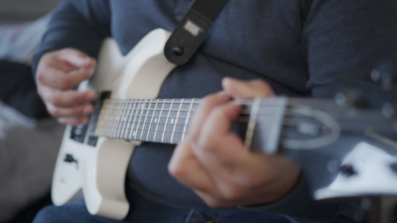 primer plano del hombre rasgueando una guitarra eléctrica