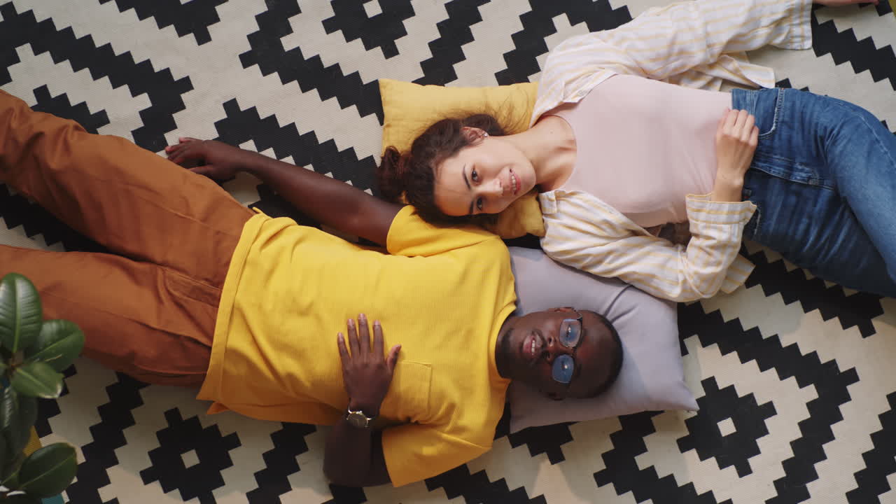 hermosa pareja multiétnica acostada en el suelo en casa