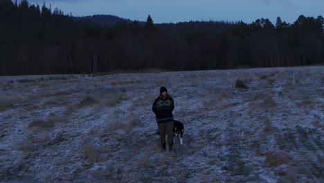 Indre-Fosen,-Trondelag-County,-Norway---A-Man-Strolls-His-Dog-Around-the-Farm-in-November---Tracking-Shot