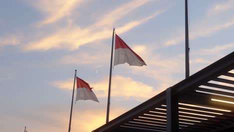 Monaco flags fluttering in the wind against a beautiful sunset sky, capturing a serene evening scene filled with national pride and coastal atmosphere.