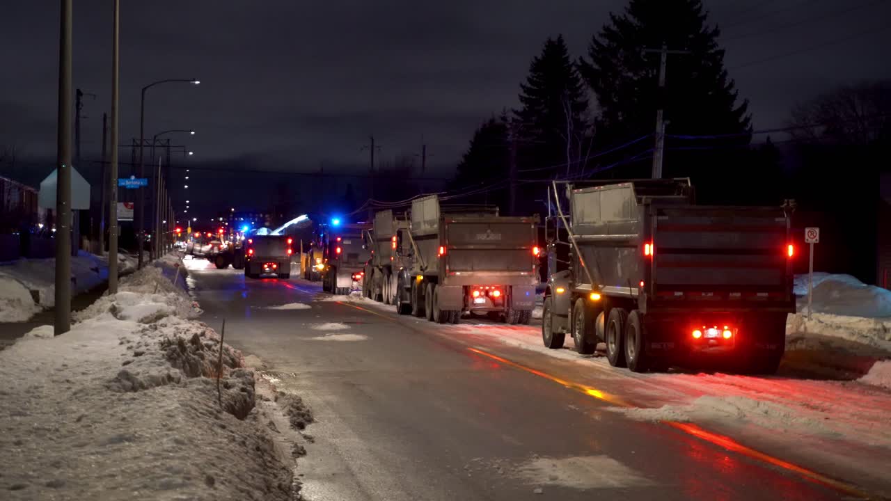 Snow removal on city streets at night.