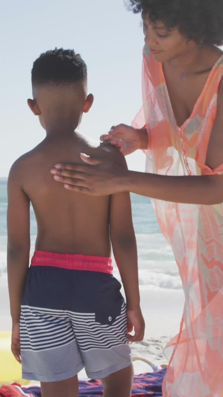 Smiling african american family using sun cream on sunny beach