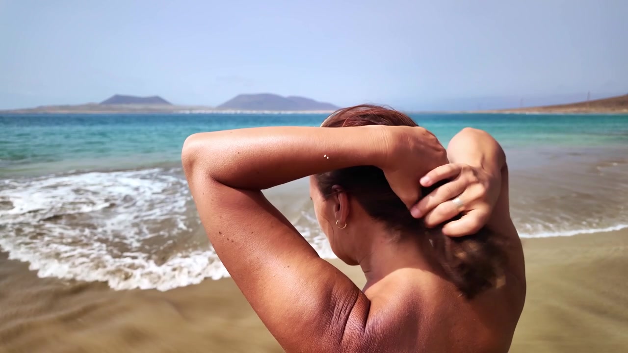 Mulher passando a mão no cabelo na praia em Lanzarote