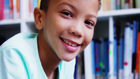 Portrait-of-schoolboy-smiling-in-library-at-school