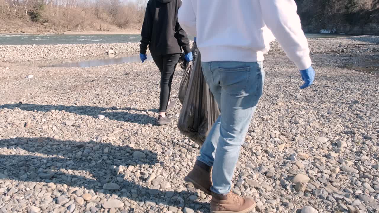 Travail d'équipe pour nettoyer le plastique sur la plage. Des bénévoles ramassent les déchets dans un sac poubelle. Concept de pollution plastique et de problème environnemental. Nettoyage volontaire de la nature du plastique. Verdir la planète