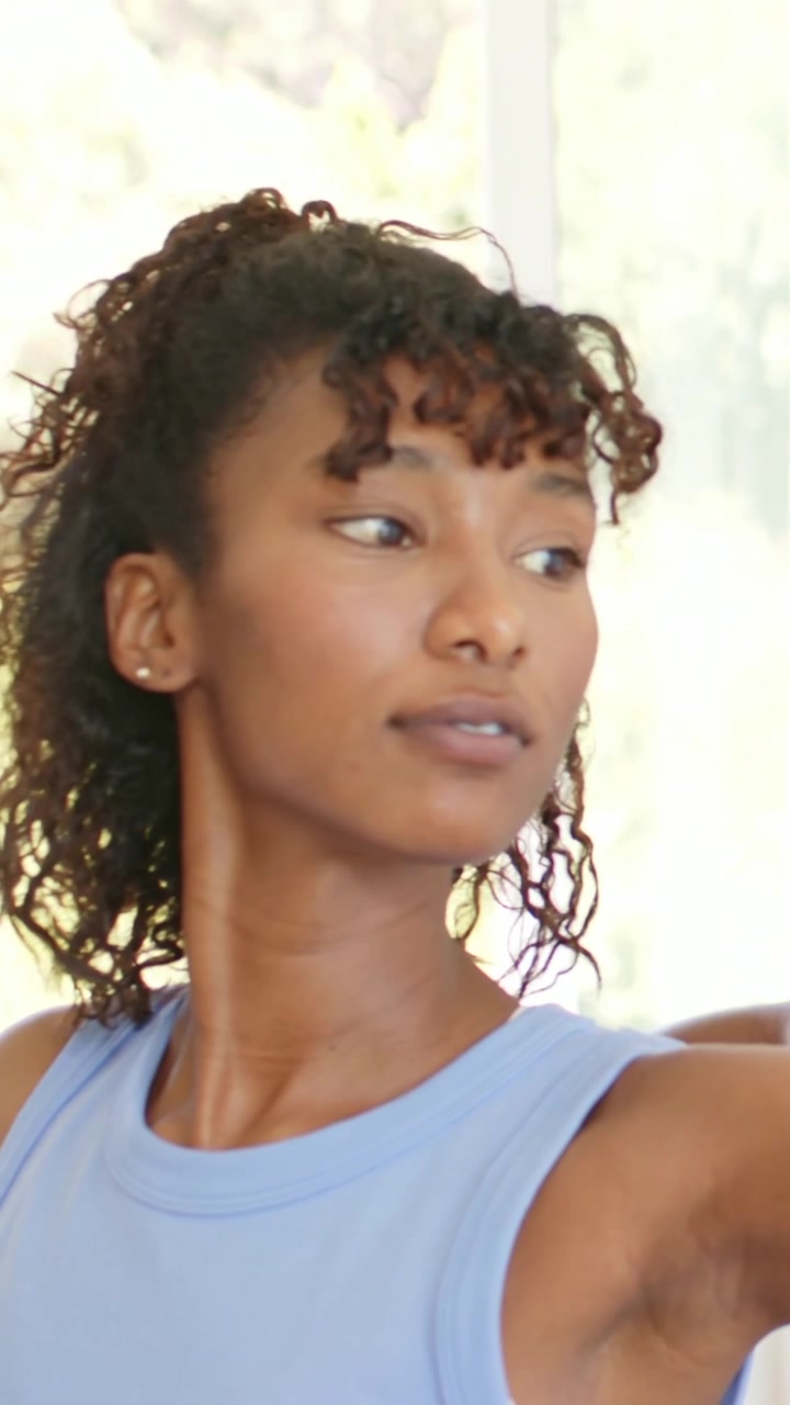 Vertical video: Woman in blue top extending arm, man guiding her for home stretch with fitness band