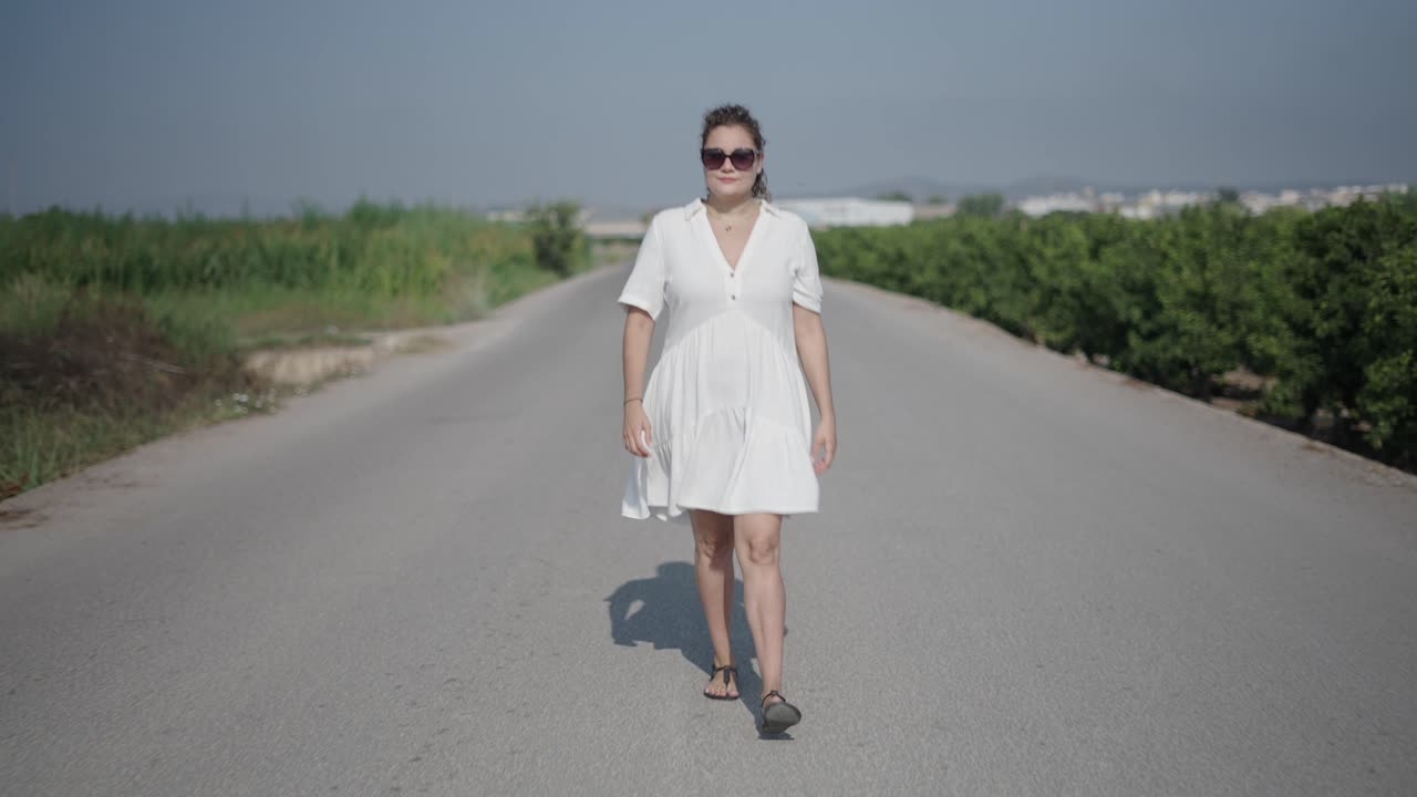 Donna che cammina su una strada di campagna in abito bianco