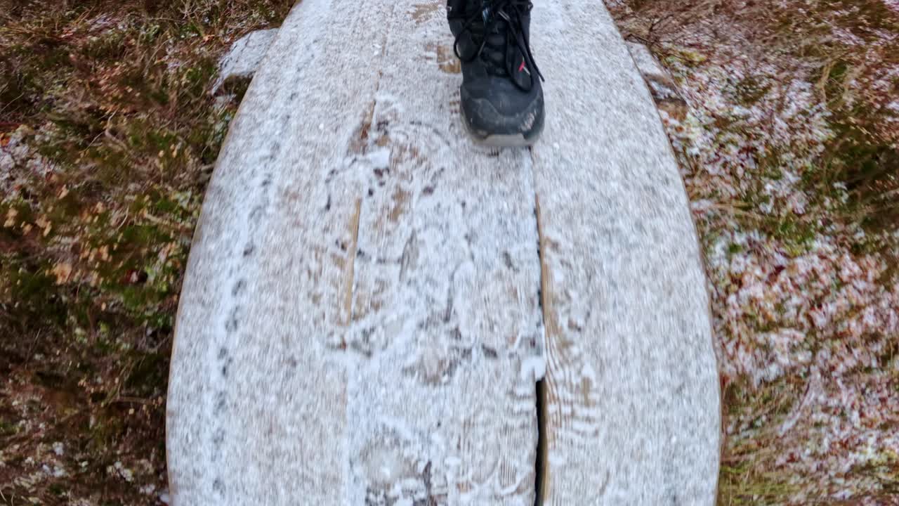 Cinematic slow motion fisheye of man walking carefully on slippery wooden path