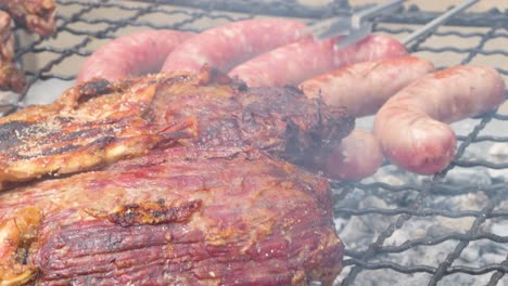 view of meat grilling on a barbecue while turning some sausages