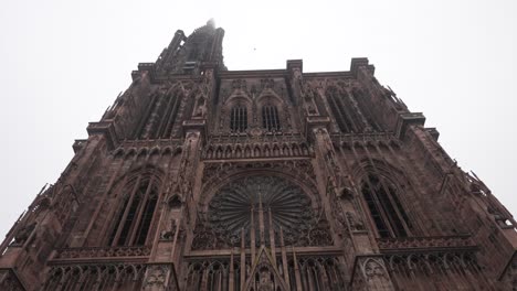 la catedral de estrasburgo, con un cielo nublado como telón de fondo, la fachada intrincadamente adornada hace señas con una serie de esculturas que representan escenas de la biblia y la vida medieval.