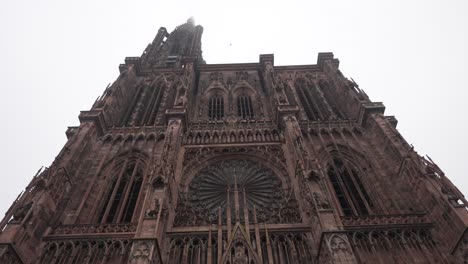 the strasbourg cathedral against a cloudy sky backdrop, the intricately adorned facade beckons with an array of sculptures portraying scenes from the bible and medieval life