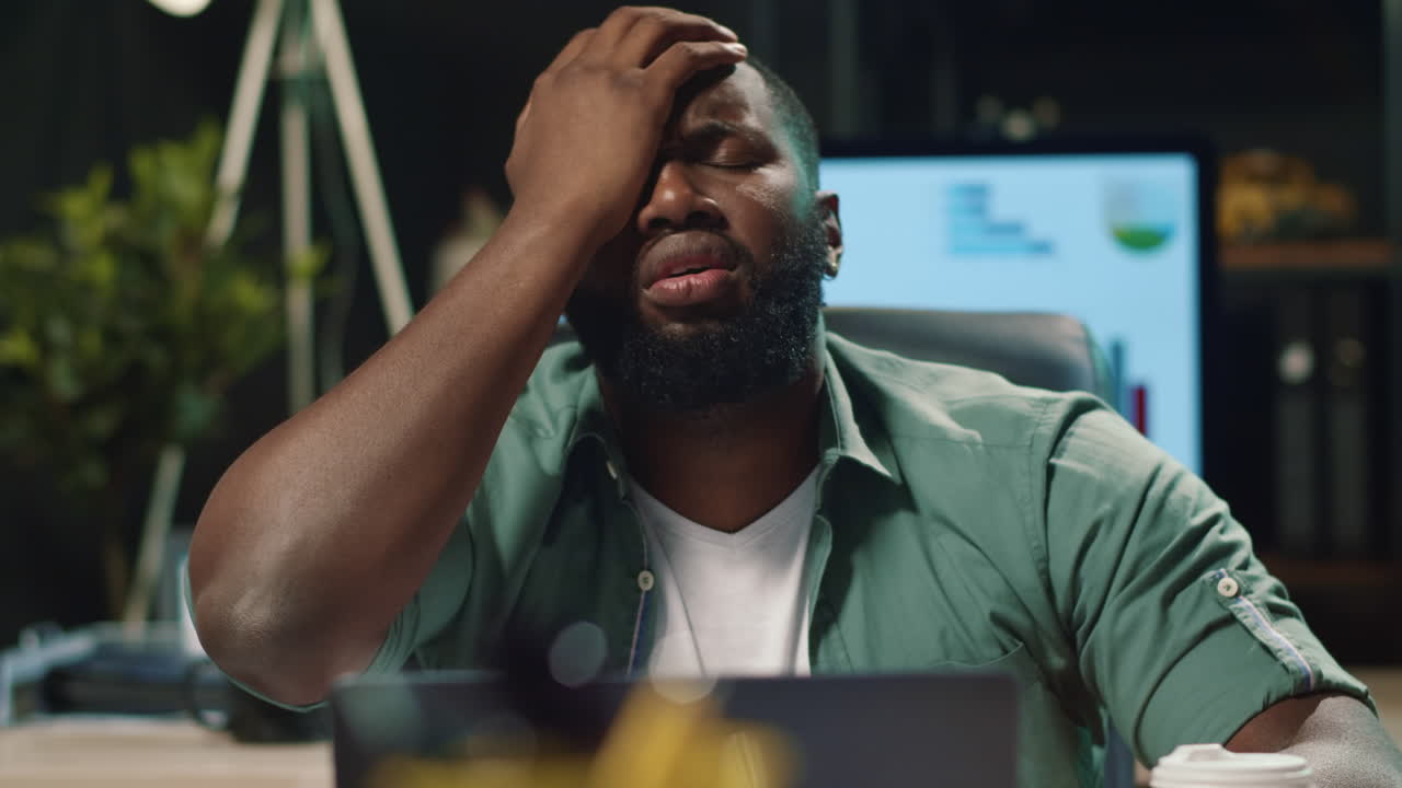 Upset afro businessman reading bad news in office. African man working laptop
