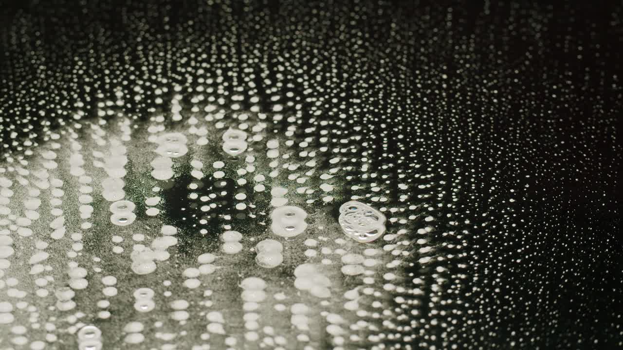 Glass with water bubbles close-up macro. Mirror texture on black background