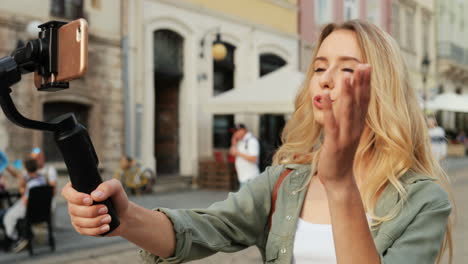 feliz bloguera de viajes contando algo mientras graba un video en el smartphone con un selfie stick en la ciudad 1