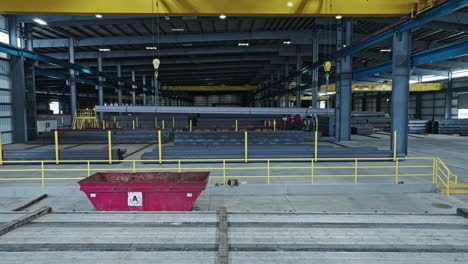 aerial dolly above empty flatbed semi truck entering into steel pipe beam warehouse