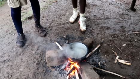 Primer-Plano-De-Un-Hombre-Africano-Sosteniendo-Una-Cuchara-Con-Café-Listo-Para-Ser-Hervido-En-Una-Olla-En-Una-Hoguera-En-El-Suelo