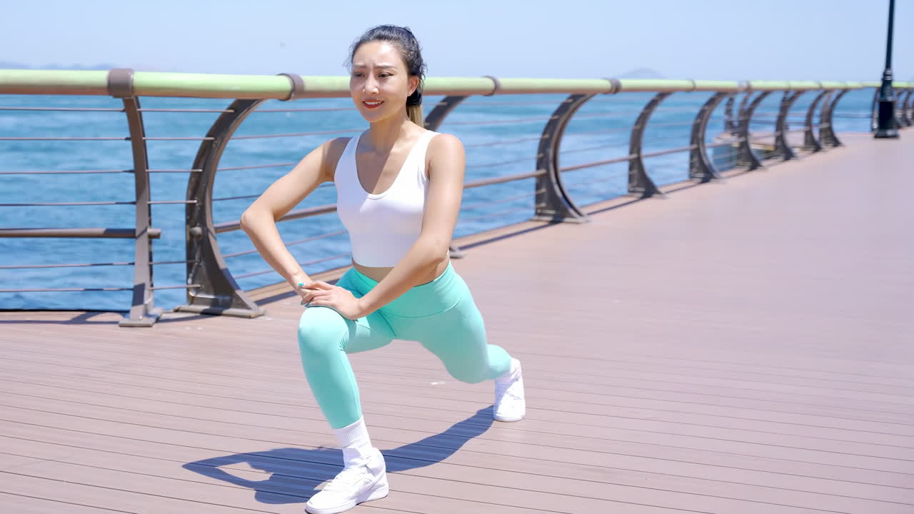 매력적인 여성, 몸을 펴고, 몸을 따뜻하게 하고, 건강하고, 웰빙을 가진 운동선수, 운동을 시작할 준비가 되어 있습니다. 바다, 울타리, 또는 피트니스 도전을 통해 야외 운동을 시작하십시오.