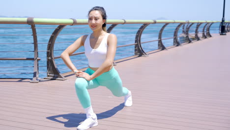 attractive woman stretching body warm up, healthy or sports athlete with wellness ready to start practice workout outdoor by sea, fence or challenge for fitness