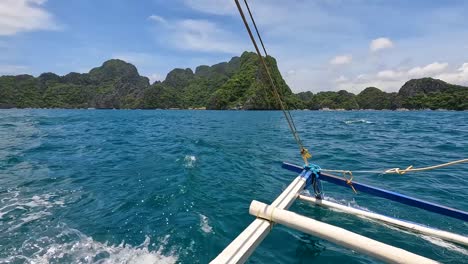 scenic landscape view of outrigger island hopping tour boat with remote tropical islands in el nido, palawan, philippines