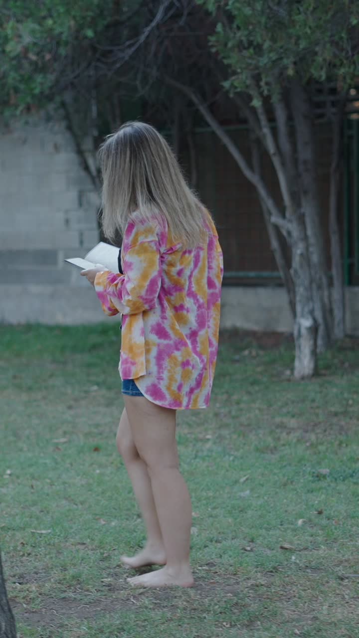Woman reading a book barefoot in a garden