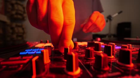 dj mixing music on turn table close up on fingers turning knobs with colored lights flashing ultra wide lens